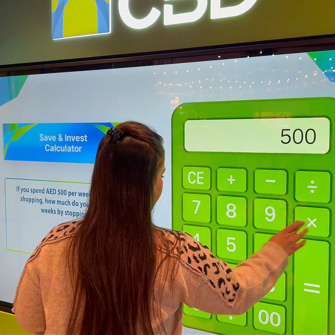 People playing a multi-level interactive financial literacy game at a brand activation event in Dubai, learning how to save and invest money.